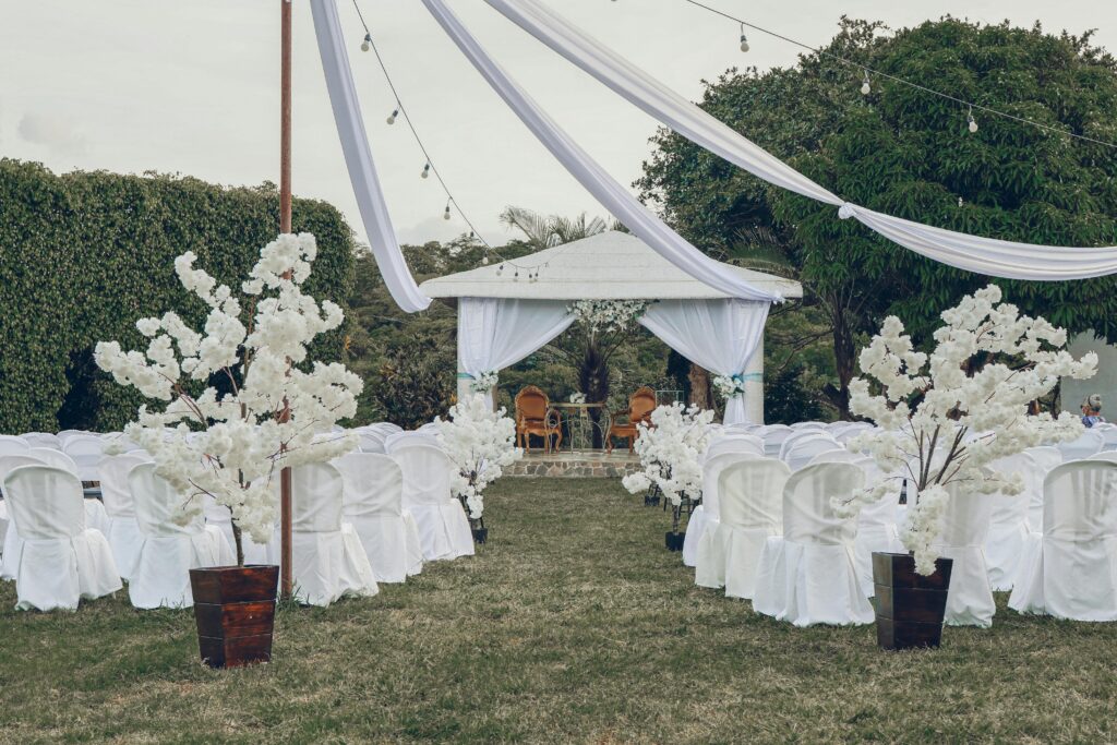Charming outdoor wedding ceremony arrangement featuring white chairs, floral decorations, and a gazebo.